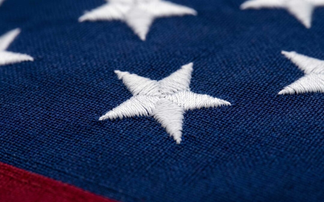 American flag close-up showing embroidered white stars on blue field with red stripe